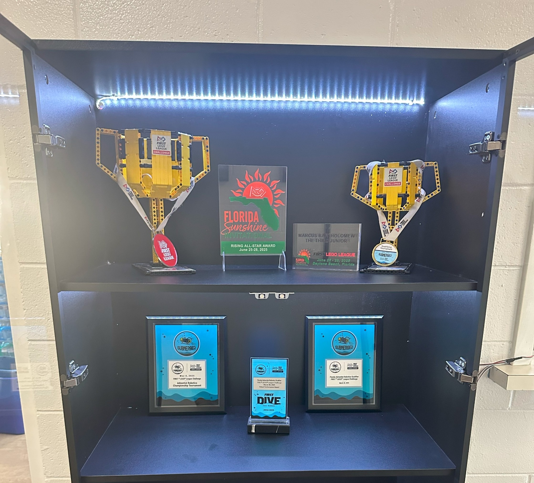 WCCA Robotics trophy case with LEGO trophies, plaques, and medals